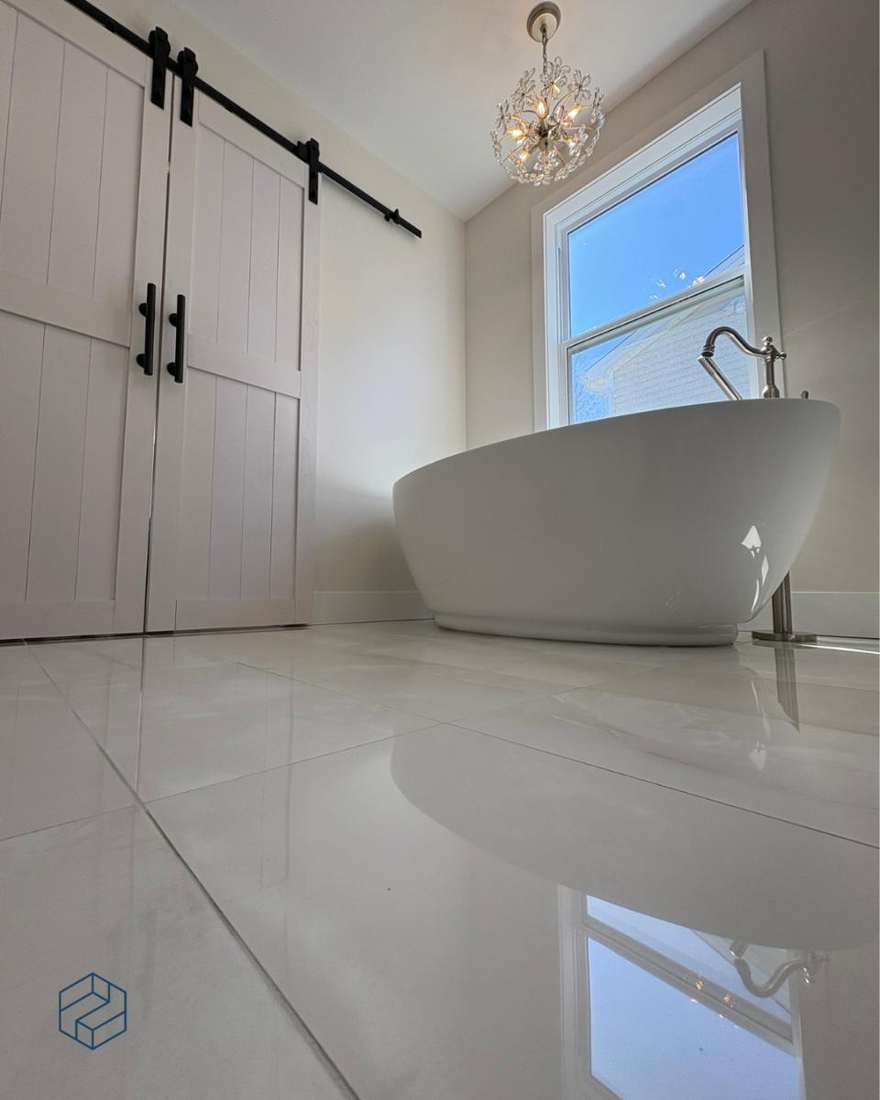 The soaking tub set beneath the window on heated marble-look tile.