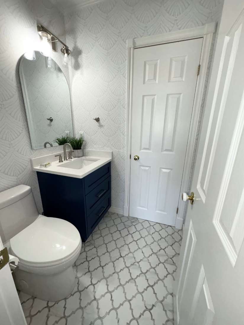 Kensington powder room — arabesque marble floor and navy cabinetry.