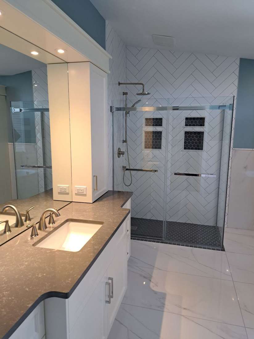 The finished Kensington bathroom — custom vanity, quartz counters and a herringbone-tiled walk-in shower.