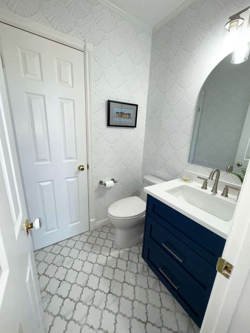 The finished Kensington powder room — navy vanity, textured wallpaper and arabesque marble floor.